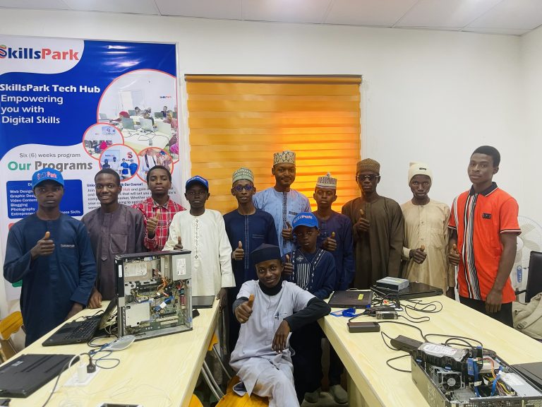 A group gathered around open desktop computers in a SkillsPark learning space.