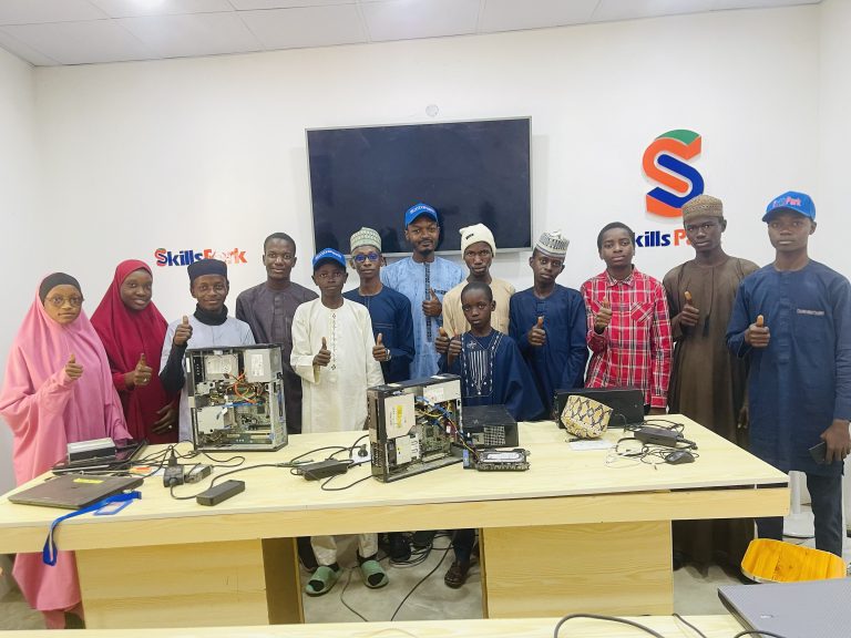 A SkillsPark hardware training group standing behind open desktop computers.